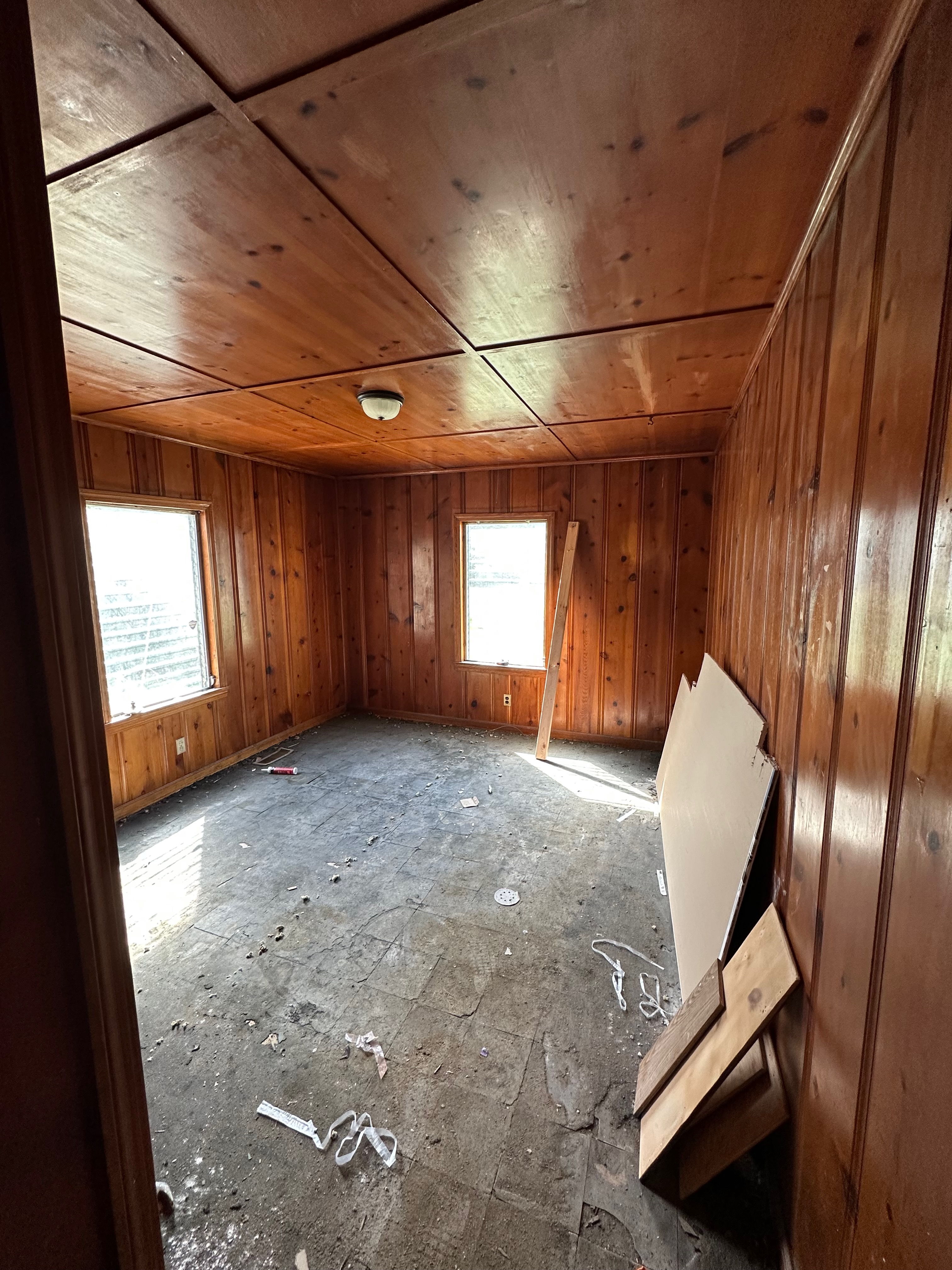 Wood-paneled room with unfinished flooring and renovation debris