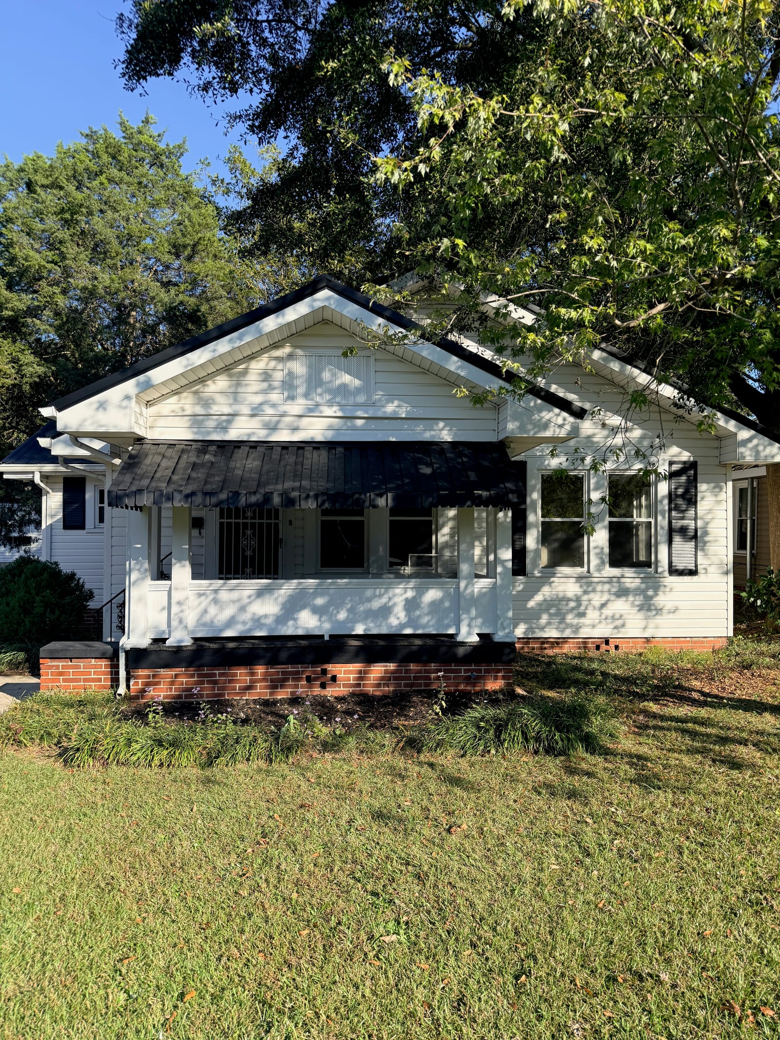 Renovated white house with black porch awning and trim