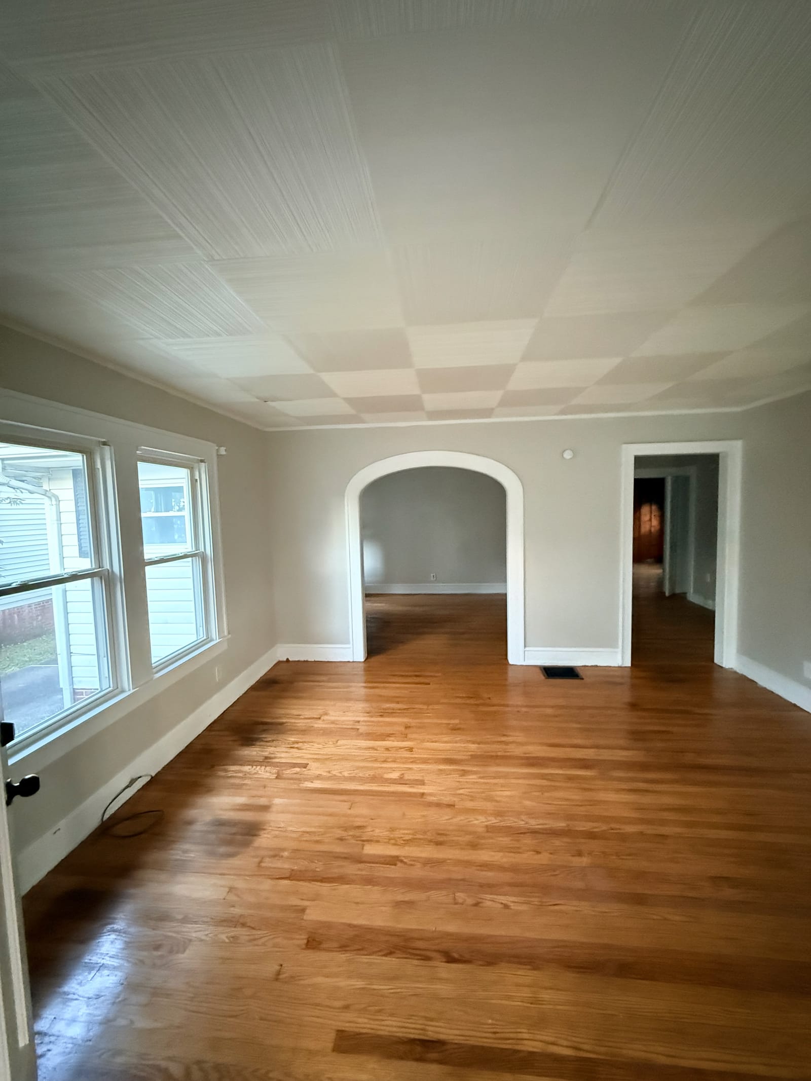 Refreshed living room with wood floors, gray walls, and an arched opening